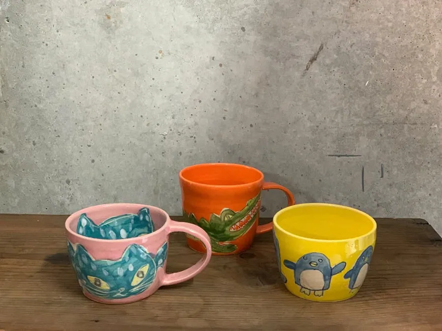 猫やワニ、ペンギンの絵が描かれたカラフルなマグカップ