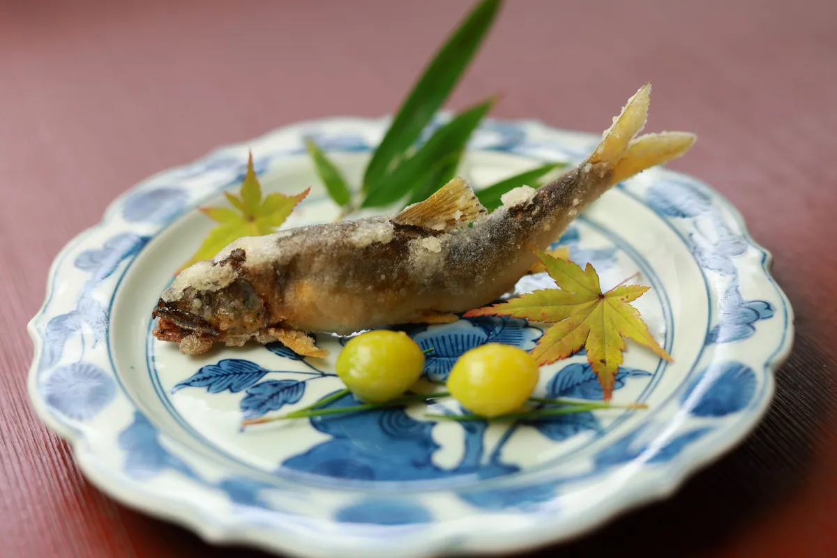 Deep-fried Yura River ayu (sweetfish) on a blue-and-white plate with a maple leaf and ginkgo nuts