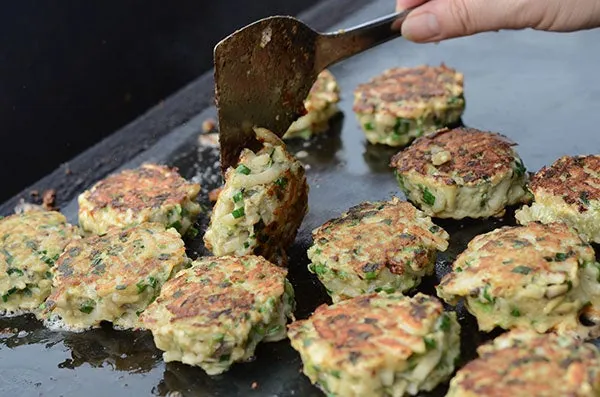 鉄板の上で焼かれる、ネギ入りの丸いギョーザのような料理