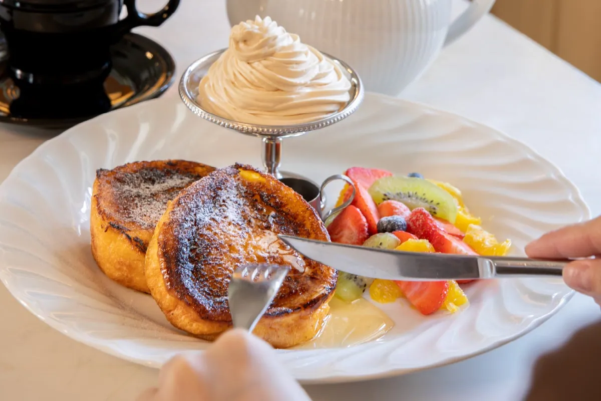 French toast with whipped cream and seasonal fruit on a white plate