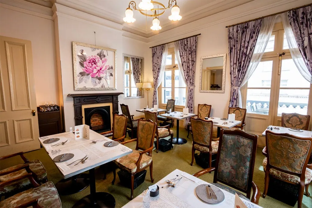 A salon dining room with a chandelier, a fireplace and a flower painting
