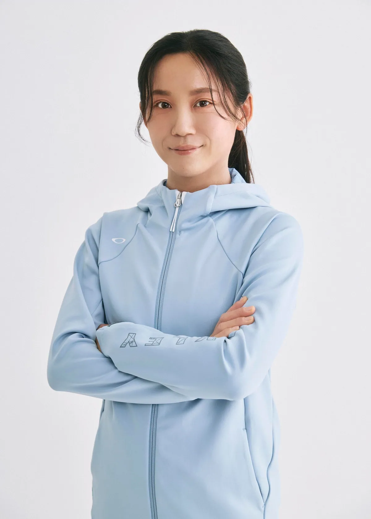 青いフード付きのウェアを着て腕を組む髙木美帆さん