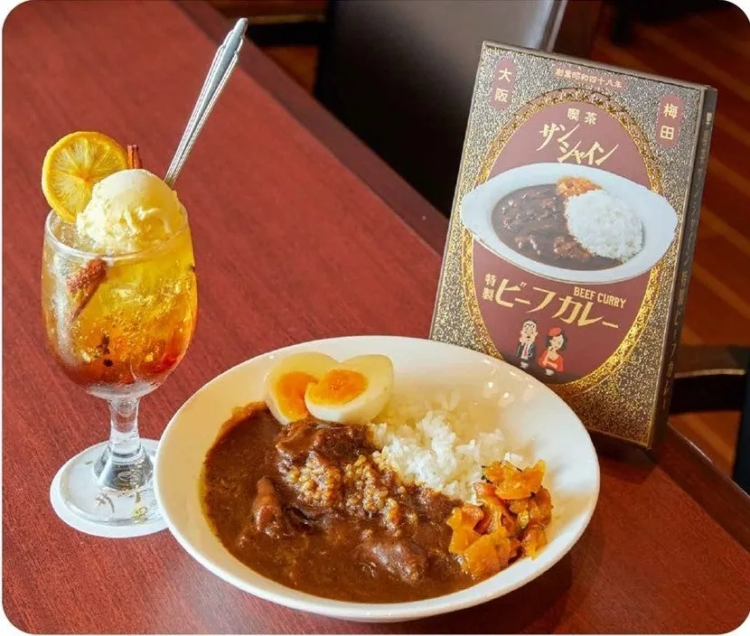 スパイスのコーラフロートと、卵をのせたビーフカレー、カレーの箱が並ぶ喫茶サンシャインのメニュー