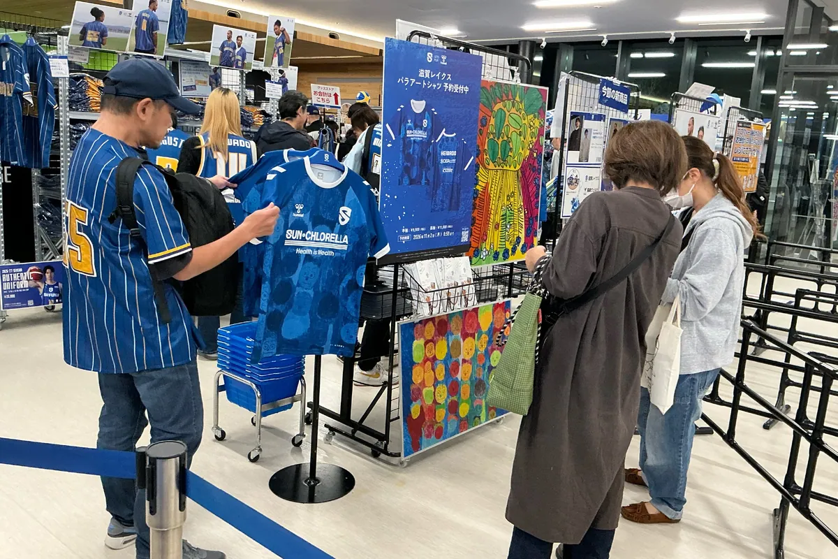 Fans browsing goods at the hummel booth, with a panel announcing para-art shirt pre-orders