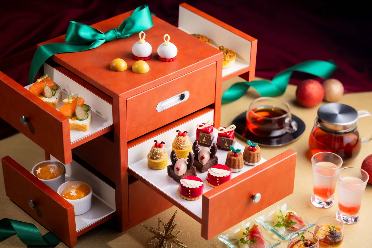 A box-shaped stand with open drawers holding Santa- and reindeer-shaped sweets for afternoon tea