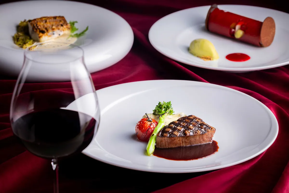 Grilled Wagyu and other festive course dishes served with a glass of red wine